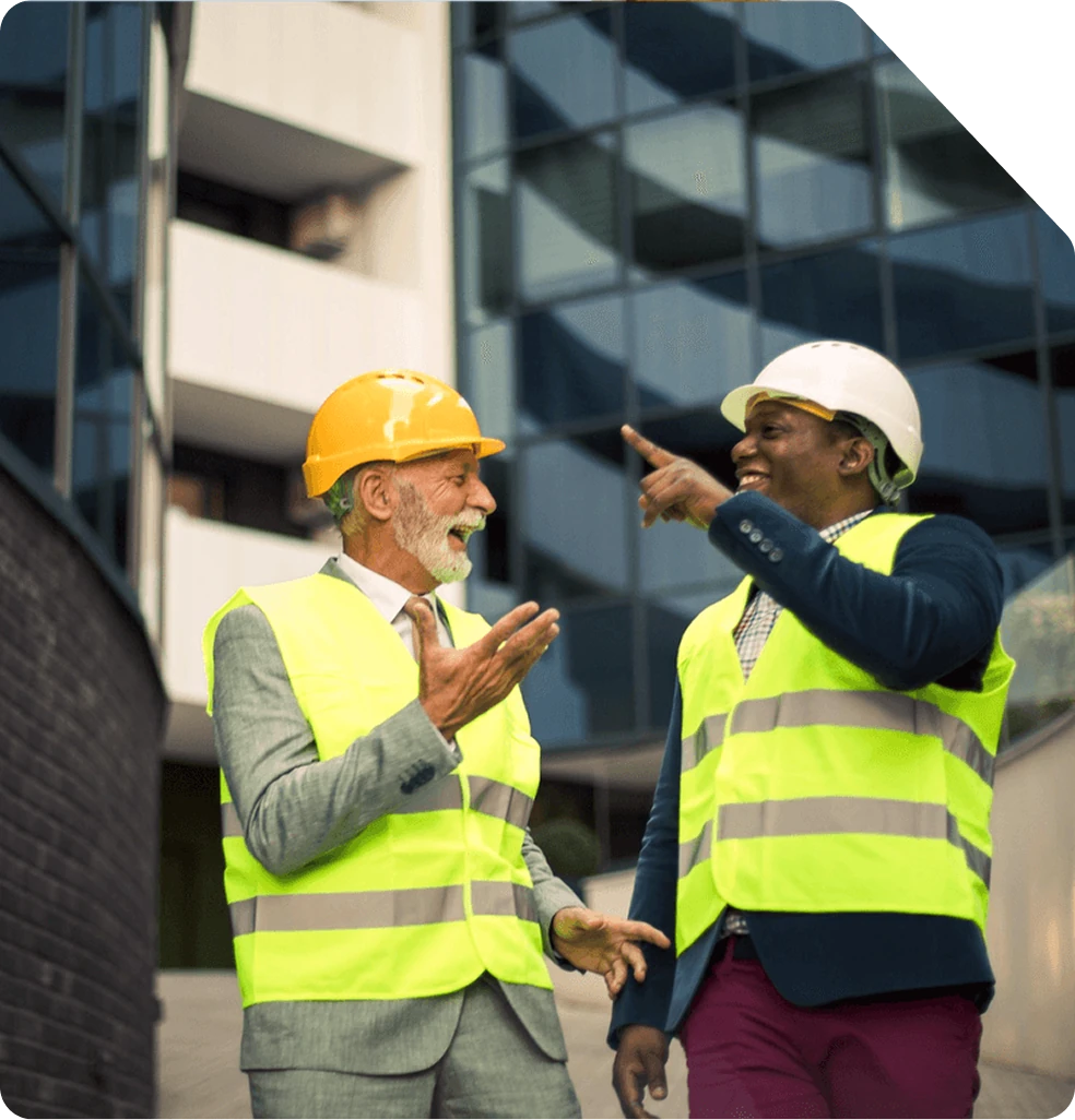Deux professionnels casqués discutant devant immeuble moderne