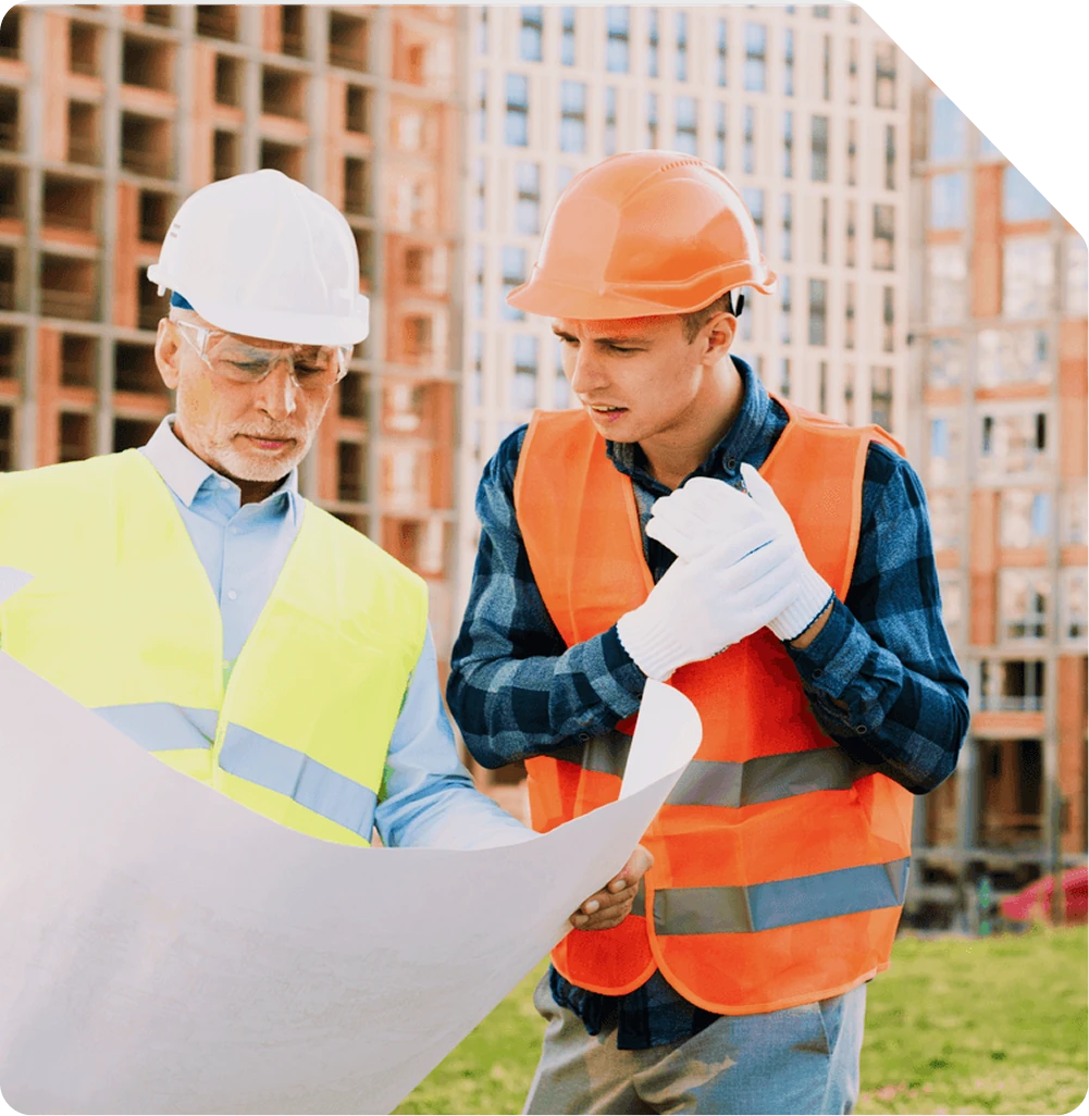 Deux ouvriers examinant des plans de chantier