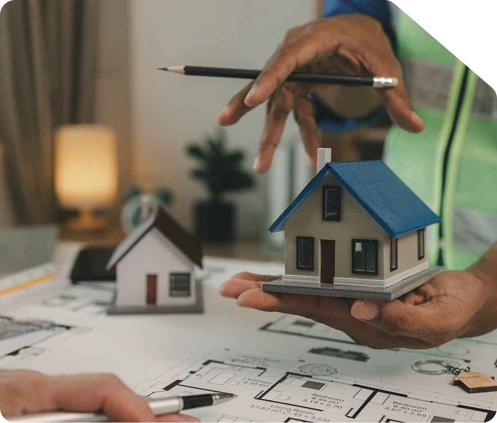 Maquette de maison tenue au-dessus de plans