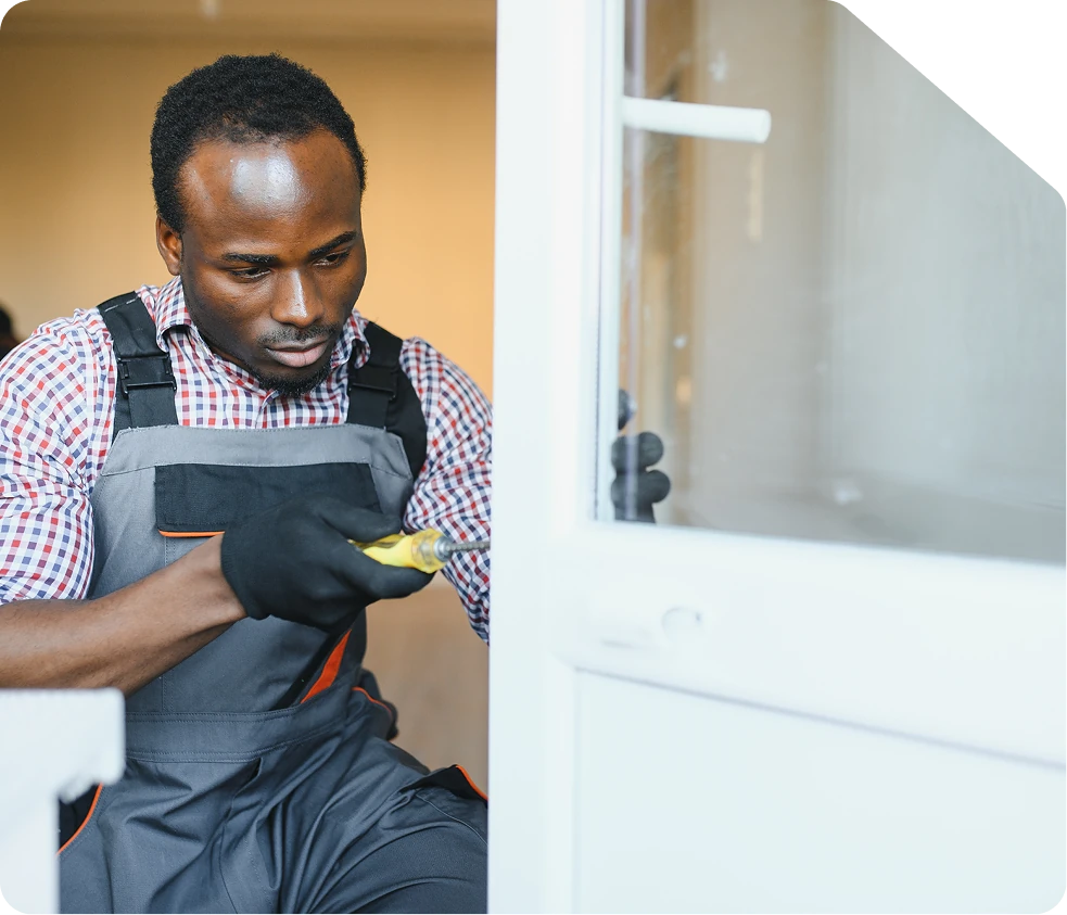 Artisan réparant une porte avec un tournevis